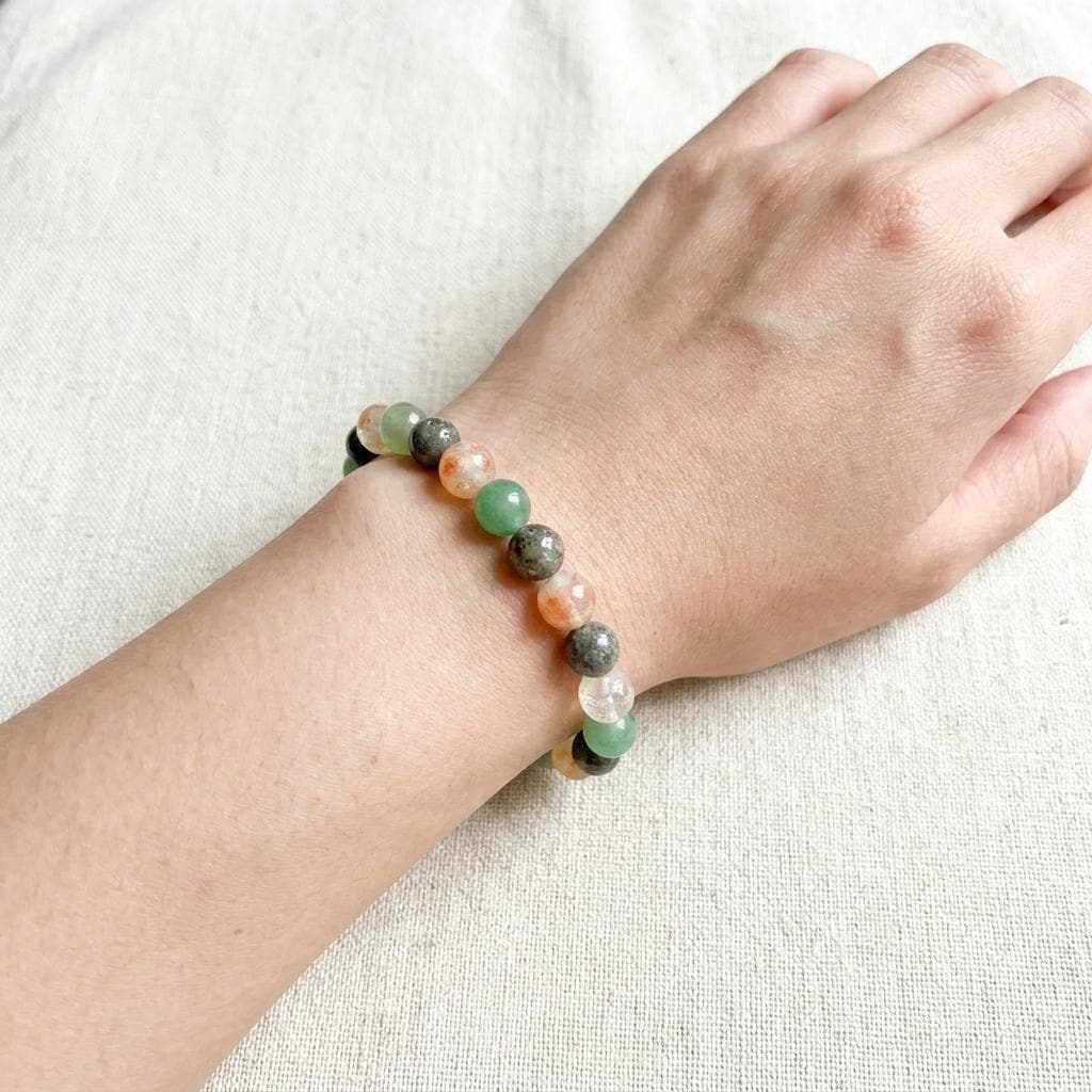 Hand wearing a bracelet with multicolored beads on a light background