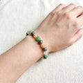 Hand wearing a bracelet with multicolored beads on a light background